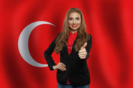 Portrait of happy woman with thumb up on Turkish flag background. Travel in Turkey