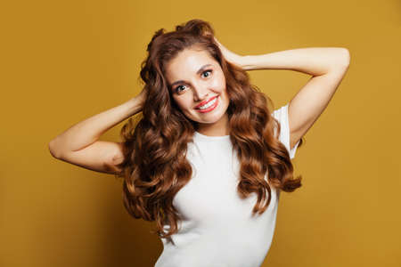 Beautiful girl in white t-shirt on yellow background. Pretty brown hair woman
