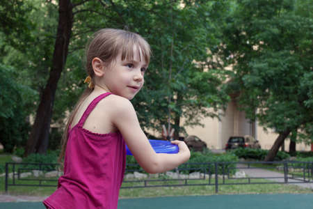 Young girl playing a plate in summer city gardenの写真素材