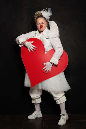 Clown Woman posing with red heart, studio portrait