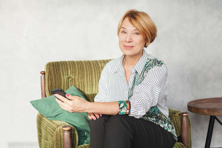 Happy mature woman used cell phone at homeの写真素材