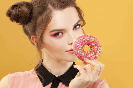 Cute woman and donut on colorful yellow backgroundの写真素材