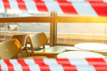 Aerport cafe lounge closed warning tape. Quarantine, canceled flight and deferred vacation conceptの写真素材