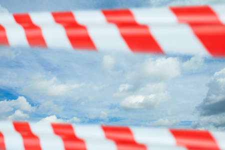 Quarantine, canceled flights and deferred vacation concept. Sky, clouds and red warning tape