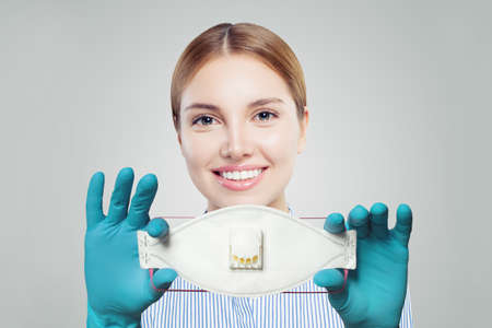 Doctor woman smiling and holding protective mask on whiteの写真素材