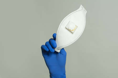 Protective mask in doctor hand on gray background, safety and virus protection conceptの写真素材