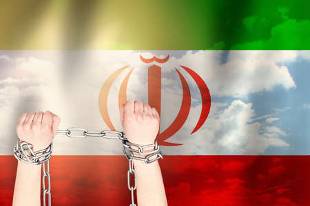 Two hands shackled a metal chain of the Iran flag. Freedom conceptの写真素材