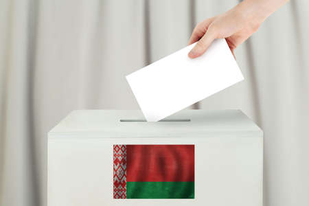 Belarusian Vote concept. Voter hand holding ballot paper for election vote on polling stationの写真素材