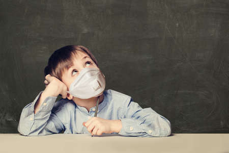 Child boy student in protective medical mask on black background with copy spaceの写真素材