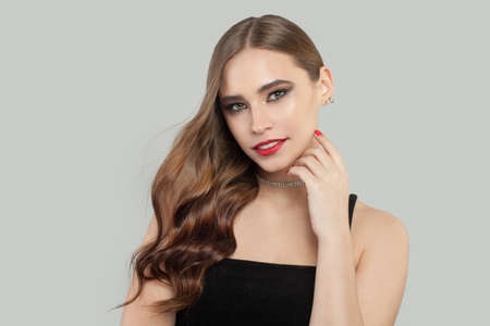 Beautiful model woman with brown curly hair and makeup on gray backgroundの写真素材