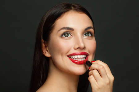 Attractive woman face with red lips and lipstick close up on black backgroundの写真素材