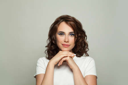 Lovely woman with brown curly hair on white backgroundの写真素材