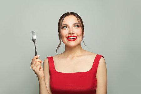 Happy woman with empty fork on white background. Food temptation.の写真素材