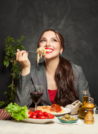 Happy woman enjoying pasta in restaurantの写真素材