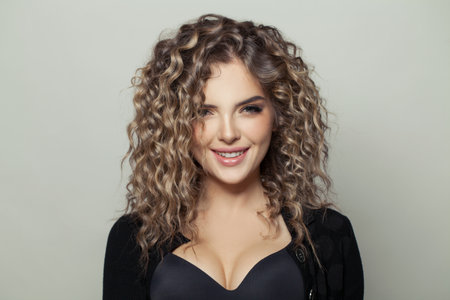 Happy woman with curly hair smiling on white backgroundの写真素材