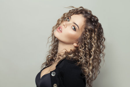 Attractive young woman with curly hairstyle on white backgroundの写真素材