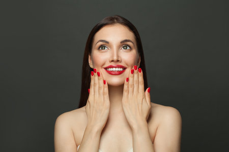 Beautiful fashion model woman with red manicured nails on black backgroundの写真素材
