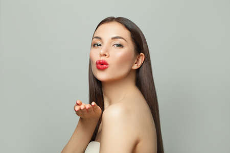 Pretty woman spa model blowing kiss on white. Skincare and facial treatment concept