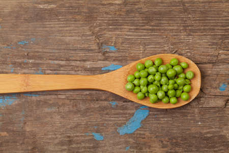 Green peas in spoon on wooden board backgroundの写真素材