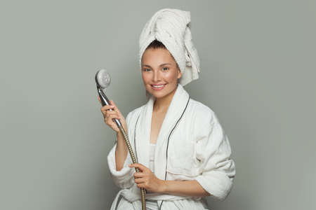 Spa model woman in white bathrobe holding shower on gray backgroundの写真素材