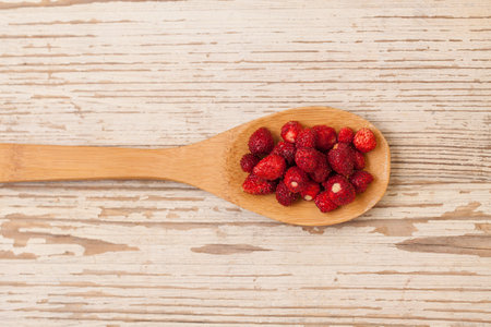 Strawberries in wooden spoon on white vintage board, organic food conceptの写真素材