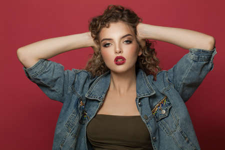 Pretty young woman with curly hair on red background
