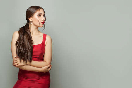 Perfect young woman fashion model in red silky dress on white banner backgroundの写真素材