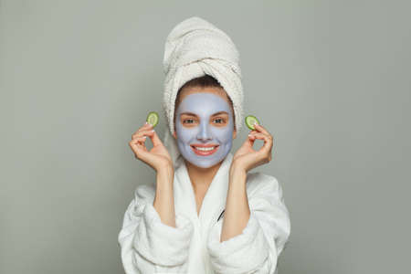 Happy woman in moisturizing cosmetic face mask with green cucumber. Facial treatment and skin care conceptの写真素材