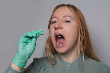 Woman with open mouth using home Coronavirus test kit. Medicine, health and Covid-19 conceptの写真素材