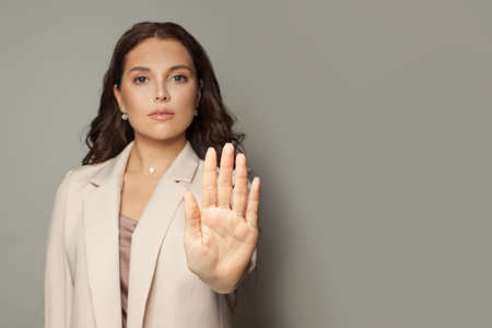 Businesswoman showing stop gesture on gray background