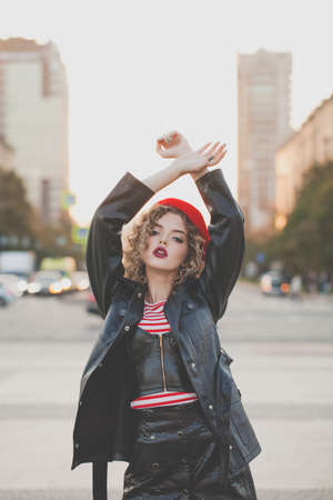 Fashion beauty portrait of stylish woman in black leather jacket and red beret posing on the street