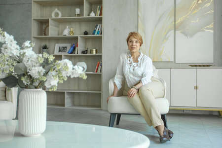 Mature lady sitting on armchair at homeの写真素材