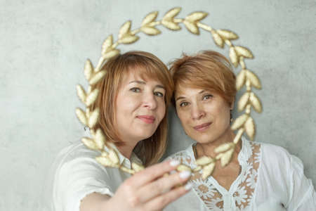 Two mature women in golden frame border portraitの写真素材