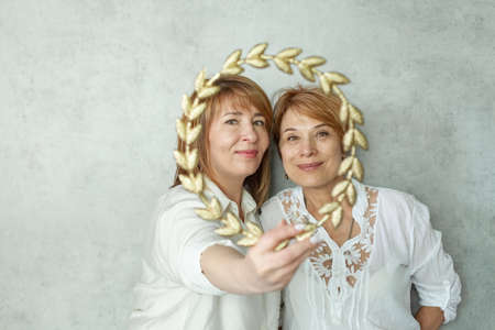 Two mature female friends hugging each other and smiling, happy meeting photo