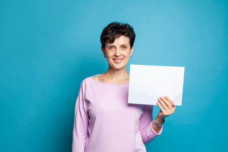 Happy smiling mature senior business woman showing white empty paper banner background