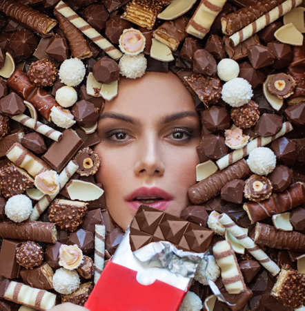 Portrait of a young beautiful woman holding a chocolate bar to enjoy the taste and food, feeling...