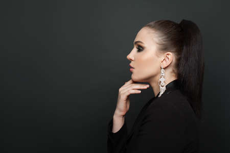 Perfect female profile on black background. Beautiful woman in diamond earringの写真素材