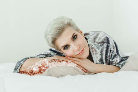 Cute woman with short hair lying on bed at home
