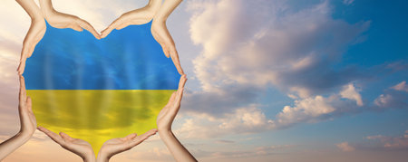 Many human hands holding heart with flag of Ukraine carefully against sky clouds backgroundの写真素材