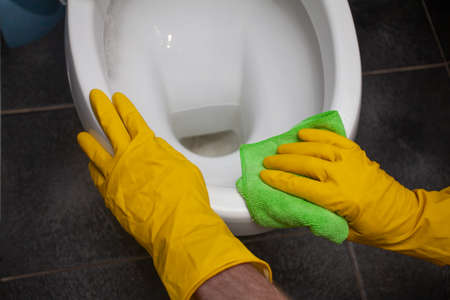 Man cleaning toilet bowl in bathroomの写真素材