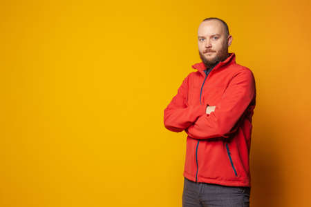 Serious man with crossed arms standing on vivid yellow background with copy spaceの写真素材