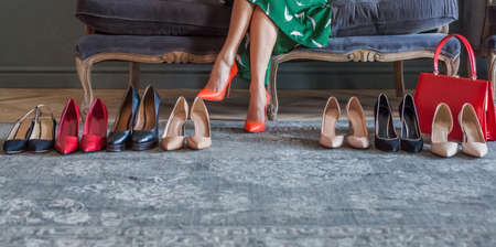 Female legs with many colorful shoes closeup. Choice and shopping concept