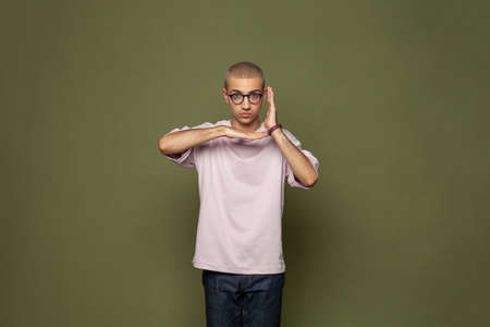 Funny young man in light pink t-shirt against green wall background