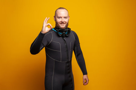 Happy cheerful man showing okay gesture on bright yellow backgroundの写真素材