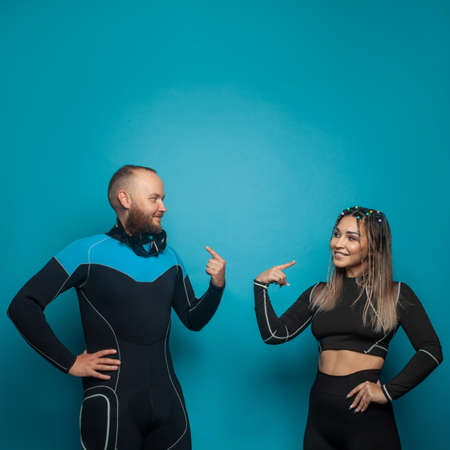 Cute friends in sportswear smiling while standing together on blue backgroundの写真素材