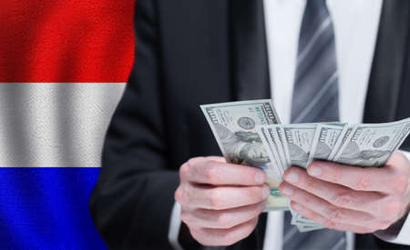 Hands holding dollar money on flag of Netherlandsの写真素材