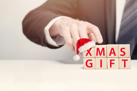 Wooden cubes with sigh xmas gift in Christmas hat, holiday, New Year business bonus, present conceptの写真素材