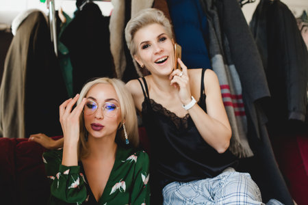 Two beautiful women are sitting together and talking on the phoneの写真素材