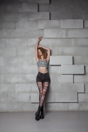 Beautiful glamorous grunge woman with torn tights and cutly hair standing in the studioの写真素材