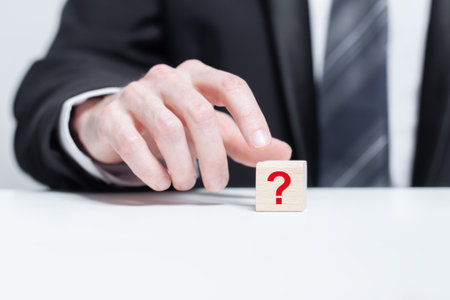 Red question mark on wooden block pyramid in businessman hand. FAQ question conceptの写真素材